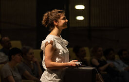 a woman in white stands at a console, looking up in enjoyment.