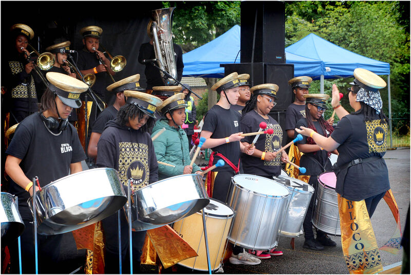 Young people playing the steel pans in a group outside.