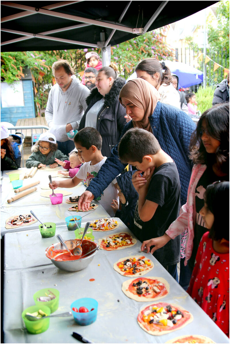 People young and old making their own pizzas ready to be cooked.