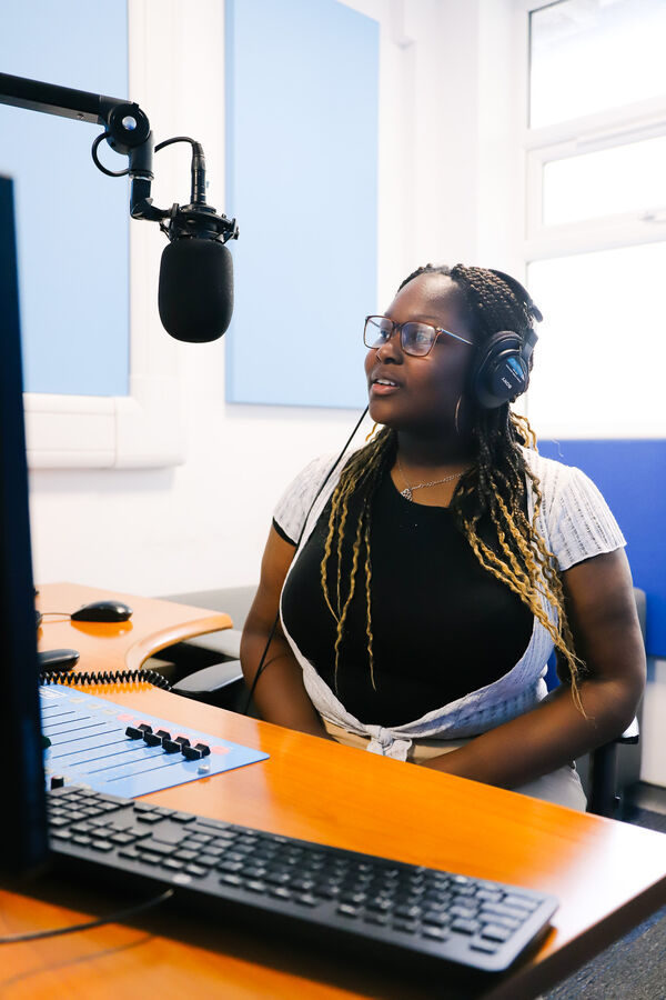 A young woman records a broadcast in a radio studio