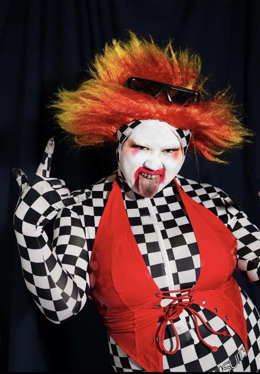 Su Mi dressed as a scary clown against a black background