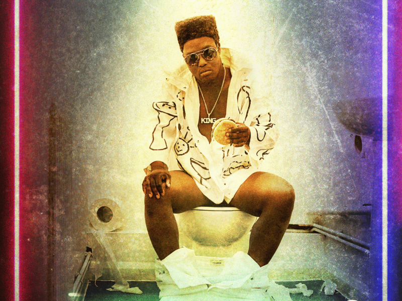Lead performer Francis dressed as Elvis, sitting on a toilet with his trousers around his ankles. He has a burger in his hand and looks into the camera.