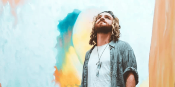 A man looking up with a painting behind him