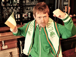Photo of Declan Duffy with Irish scarf and flag leaning against a bar in a pub