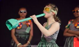 A Young Person Performs Blowing  A Trumpet Like Object Wearing Goggles Onstage