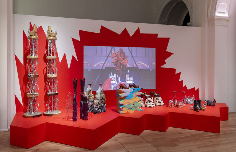 Unidentified Performing Objects shoe-sculptures in various colours and forms by artist Luca Bosani, red spiky background, performance film in the centre, V&A Museum South Kensington, Gallery 29, 2024-2025