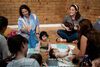 A group of mothers and babies sitting on the floor and singing together