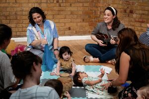 A group of mothers and babies sitting on the floor and singing together
