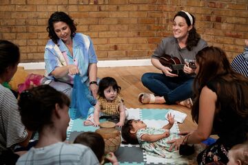 A group of mothers and babies sitting on the floor and singing together