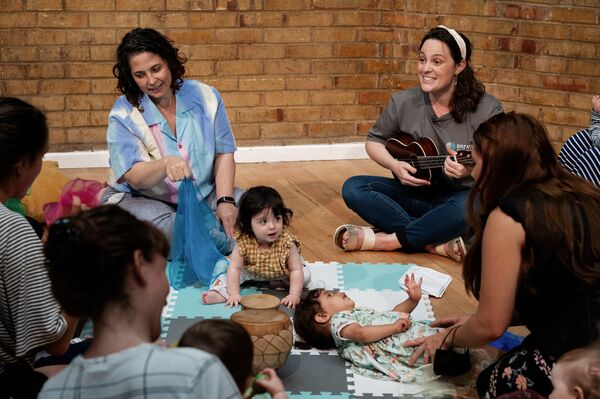 A group of mothers and babies sitting on the floor and singing together