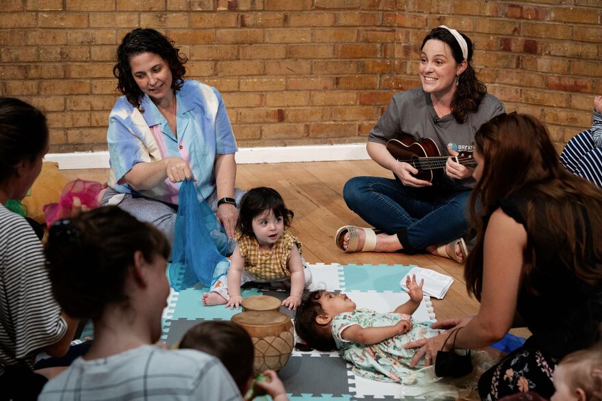 A group of mothers and babies sitting on the floor and singing together