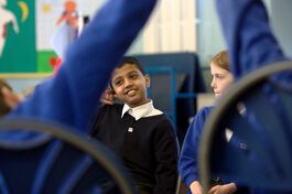 Two primary schools pupils in blue uniforms participate in classroom workshop