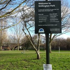sign with park with green behind
