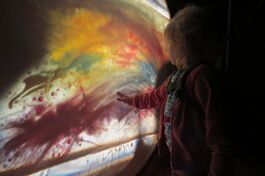Young child feels a colourful projection