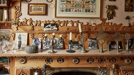 An intricately decorated mantel piece with candles, black and white photos and wooden carvings