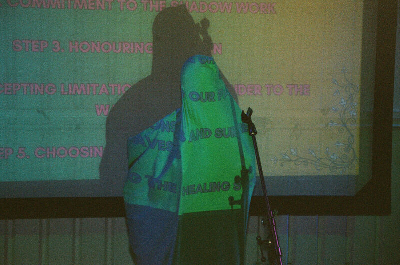 An artist performing in front of a projected image under a sheet