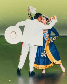 Two Peruvian dancers in traditional dress are captured in a pose as they dance.