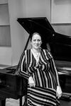 Woman standing in front of piano smiling