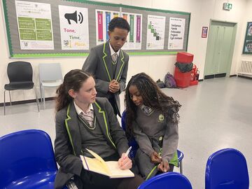 Three children in uniform discuss notes