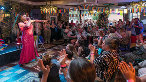 A singer in a pink dress points to the joyful audience