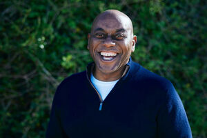 Ainsley Harriott laughing in front of hedge background