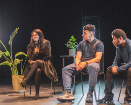 Three seated young people speaking at a round table discussion.