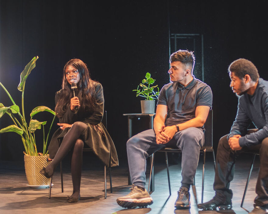 Three seated young people speaking at a round table discussion.