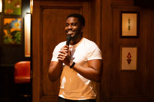 A young black man smiling with a microphone
