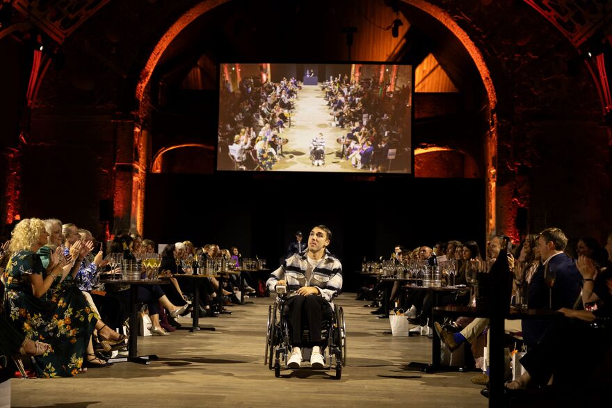 The picture shows actor George Robinson in a wheelchair, modelling on the catwalk at Front Row 2025