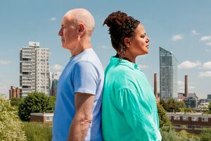 a man and a woman stand back to back against a wandsworth backdrop