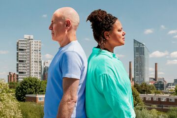 a man and a woman stand back to back against a wandsworth backdrop