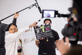 A film crew member holds a clapperboard labeled 