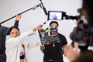 A film crew member holds a clapperboard labeled 