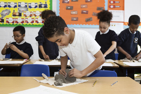 young boy modelling with clay in classroom