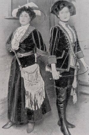 Black and white photograph of two women actors. One of them dressed as a male and the other as female.