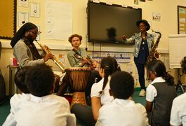 three musicians face a class of children