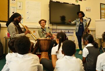 three musicians face a class of children