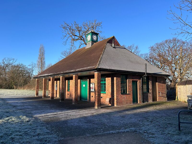 a photo of the north side of the pavilion, a red brick building with a clock tower on the roof and 6 pillars in the front. 