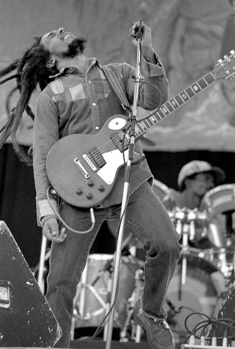 Bob Marley performing in Dublin in July 1980. He has a guitar strapped loosely to him and the image captures his movement as he performs