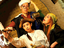 Three actors swapping pirate costumes and holding props in a chaotic fashion