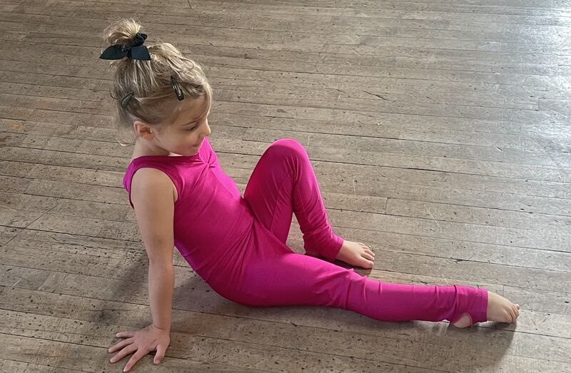 A three year old girl performing a foot exercise to a story with music