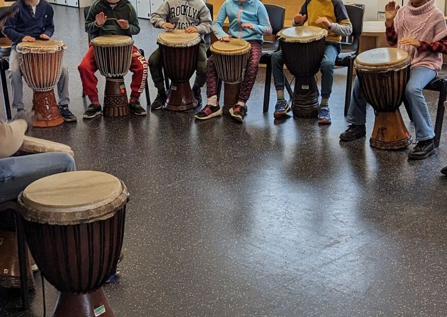 Group of children playing djembe drums