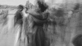 motion blurred image of two people holding each other as they dance by the River Thames