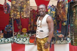 Man stands in front of stall of traditional african clothes.
