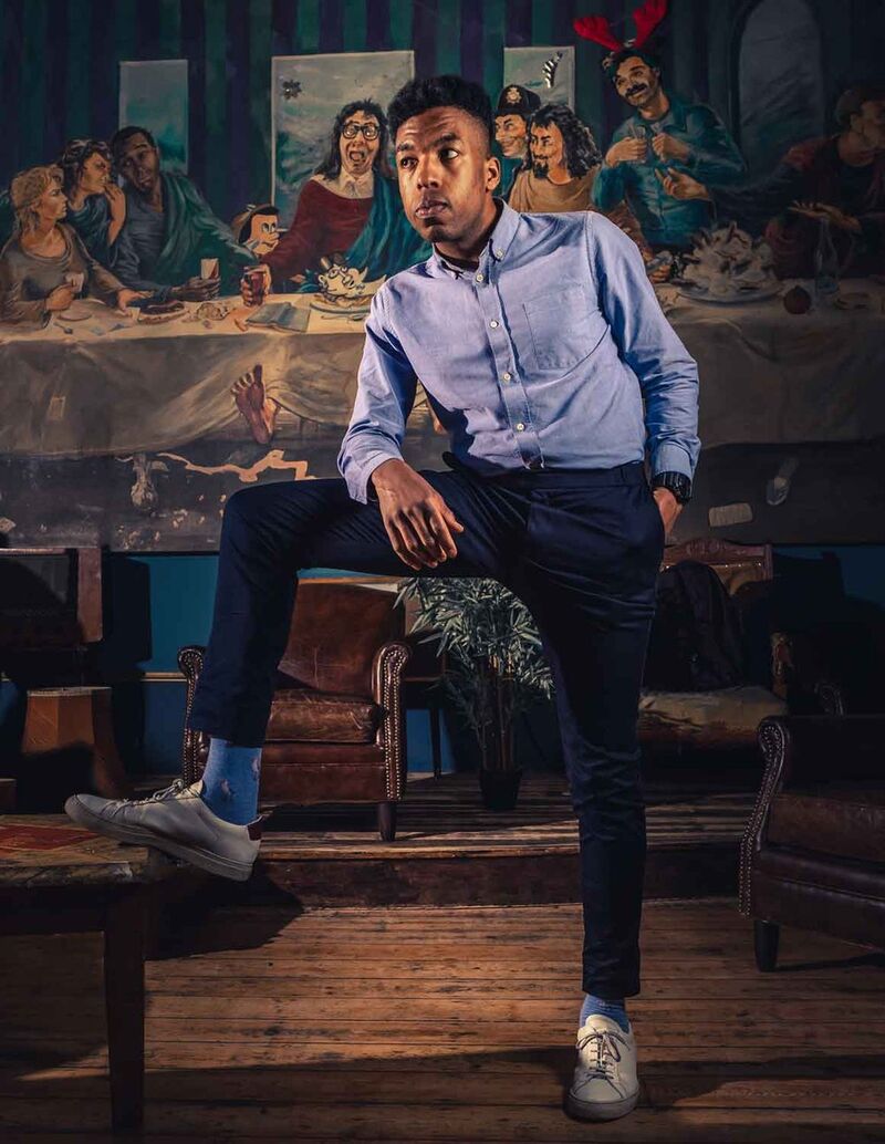 Toussaint Douglass stands coquettishly in front of a painting.
