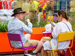 Two people sitting on colourful tables.