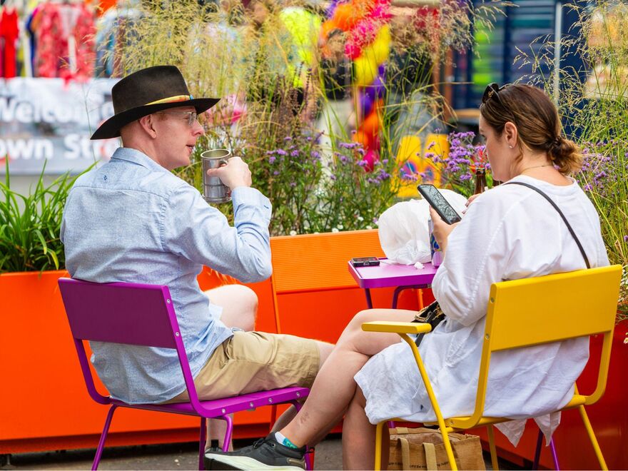 Two people sitting on colourful tables.