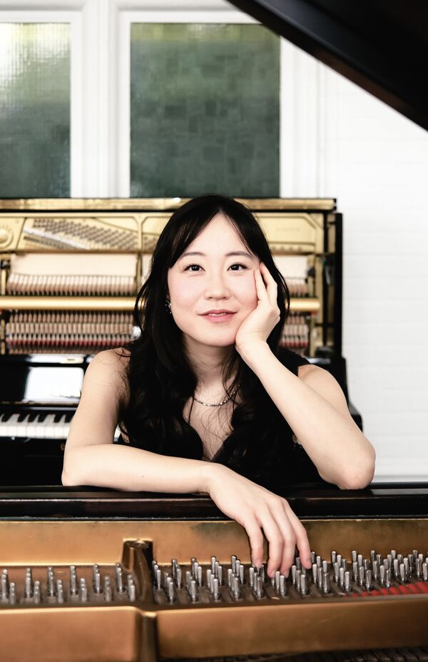 A Woman Sits Leaning On A Piano Smiling