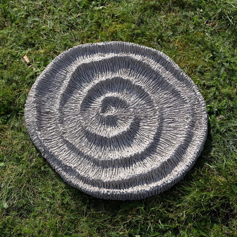 a large spiral clay sculpture on a bright green grass background