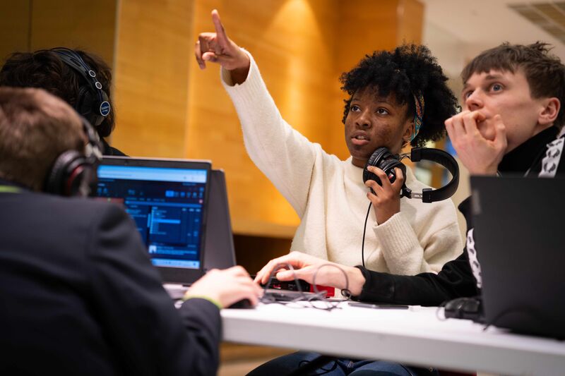 A young participant points off-camera during a music production workshop